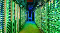 The blinking lights of racks of Google servers glow in a darkened data hall in St. Ghislain, Belgium. (Image: Google)