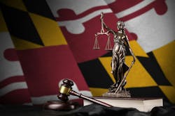 Maryland State Flag behind Lady Justice figurine and gavel. Maryland State Flag behind Lady Justice figurine and gavel.